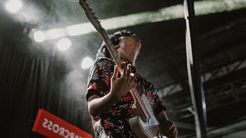 leisure activities man wearing black and red floral collared button-up shirt standing while playing electric guitar musical instrument